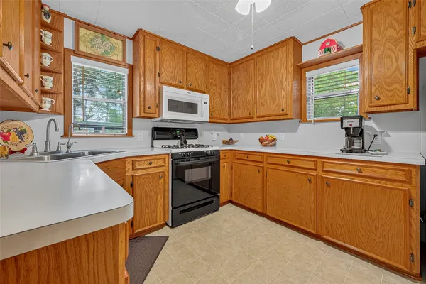 a kitchen with stainless steel appliances granite countertop a sink a stove a refrigerator cabinets and a window