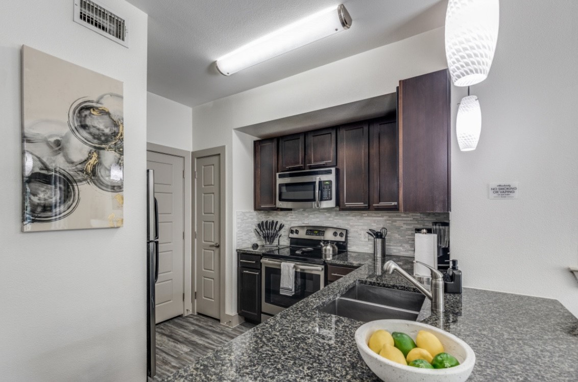 145 Heights Boulevard, Unit 229 Houston, TX 77007 - Photo 4 of 12 a kitchen with stainless steel appliances granite countertop a stove a sink and a microwave