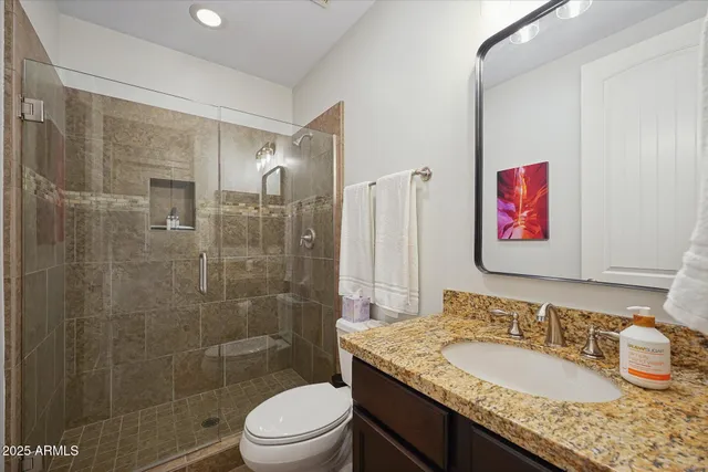 a bathroom with a granite countertop sink a toilet and a shower
