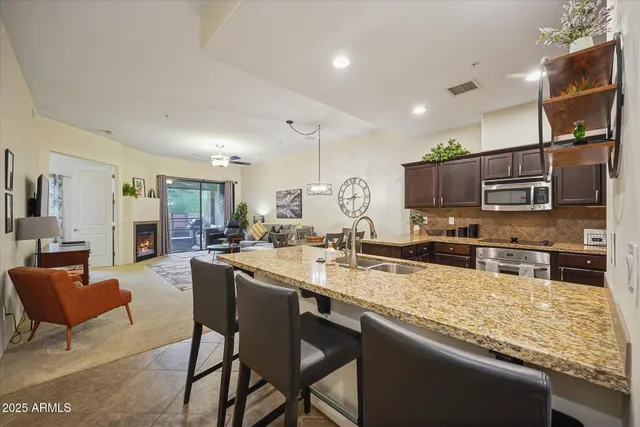 a kitchen with stainless steel appliances granite countertop a stove top oven a sink dishwasher a dining table and chairs with wooden floor