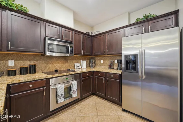 a kitchen with stainless steel appliances granite countertop a refrigerator a stove a sink and dishwasher