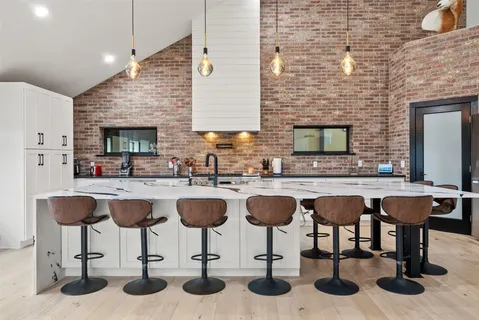 a kitchen with a granite countertop sink and chairs
