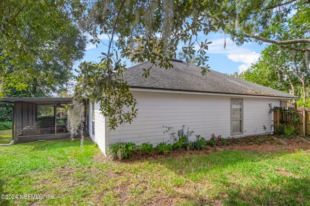 a view of a house with a yard plants and large tree