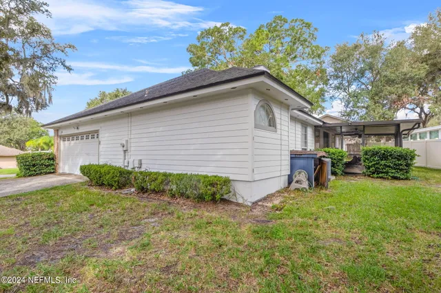 a backyard of a house with potted plants and a large tree