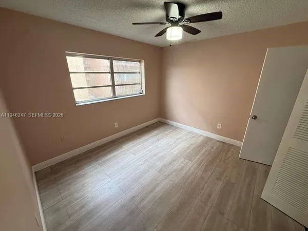 an empty room with wooden floor fan and windows