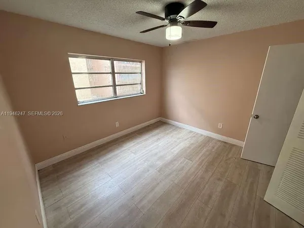 an empty room with wooden floor fan and windows