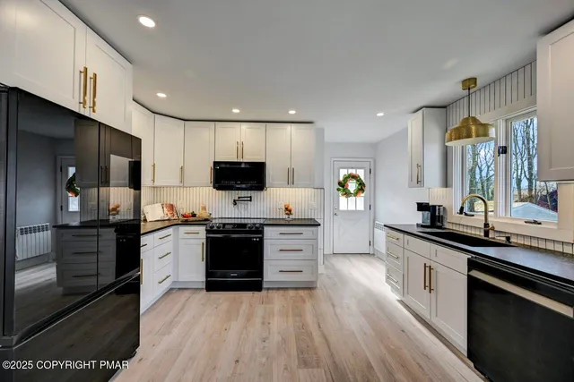 a kitchen with stainless steel appliances a sink dishwasher a stove and a microwave oven with wooden floor