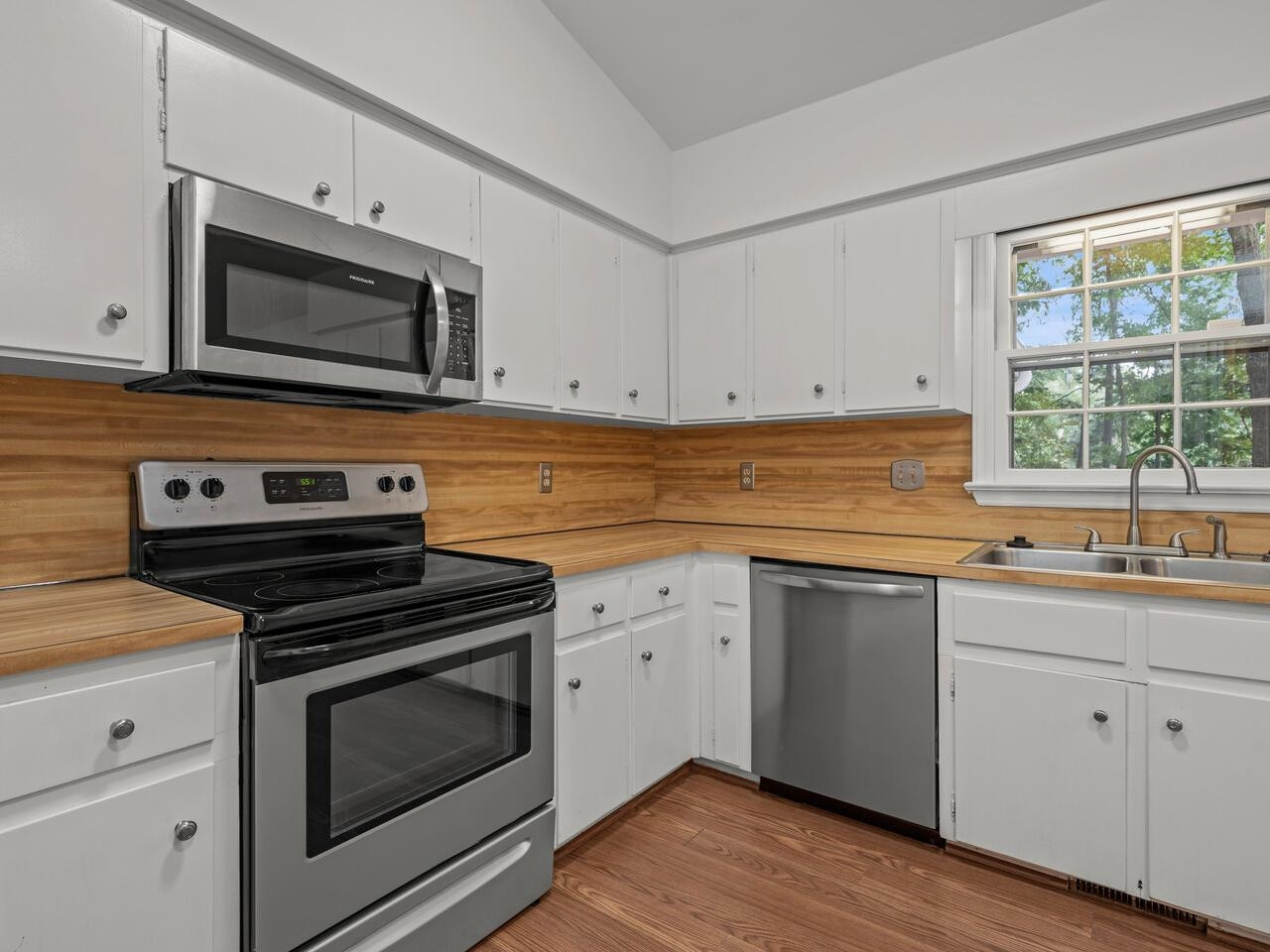 4504 Wenchelsea Place Raleigh, NC 27612 - Photo 11 of 27 a kitchen with cabinets stainless steel appliances a sink and a window