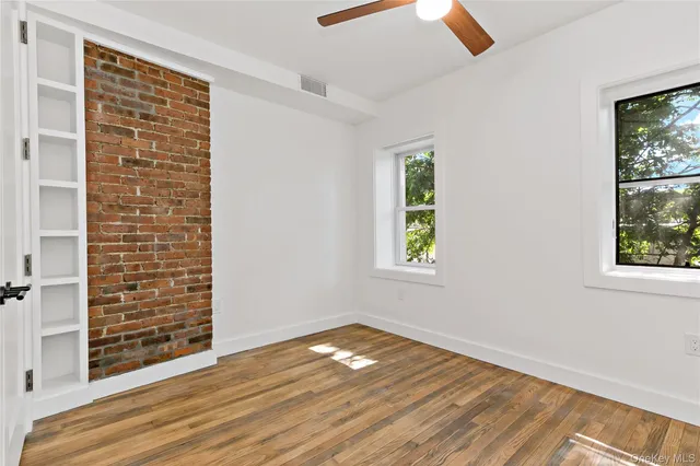 an empty room with wooden floor cabinet and windows