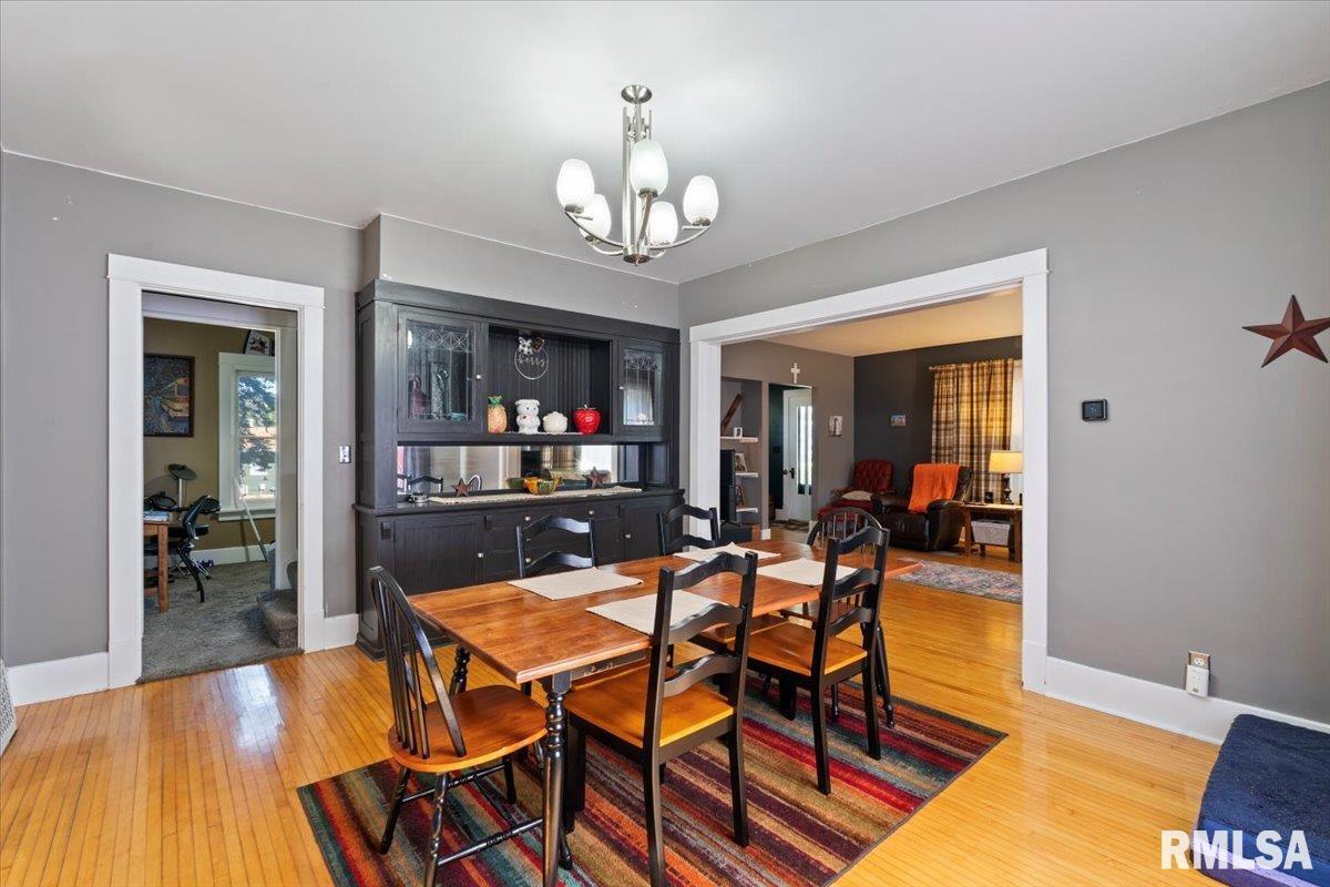 101 South Stewart Street Geneseo, IL 61254 - Photo 20 of 41 a dining room with wooden floor a chandelier a glass table and chairs