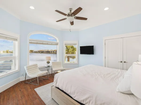 a bedroom with a bed and a large window with wooden floor