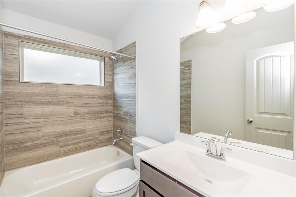6447 Escondido Drive Rosharon, TX 77583 - Photo 6 of 16 Relax and unwind in this beautifully designed bathroom featuring a soaking tub with stunning tile surround, modern fixtures, and a spacious vanity. The frosted window allows for natural light while maintaining privacy, creating the perfect balance of style and function. Ideal for rejuvenation after a long day.
