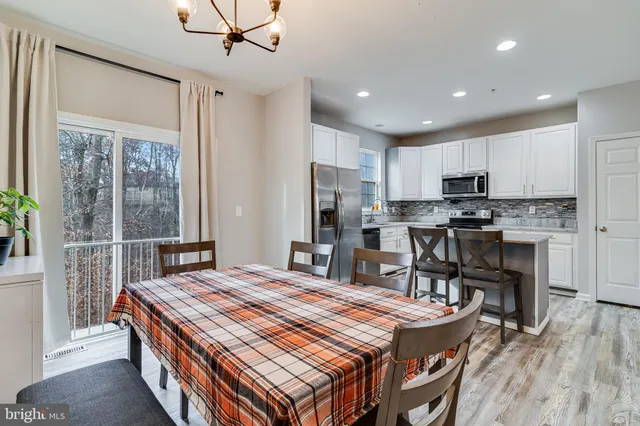 a kitchen with kitchen island a stove a refrigerator a sink a dining table and chairs with wooden floor