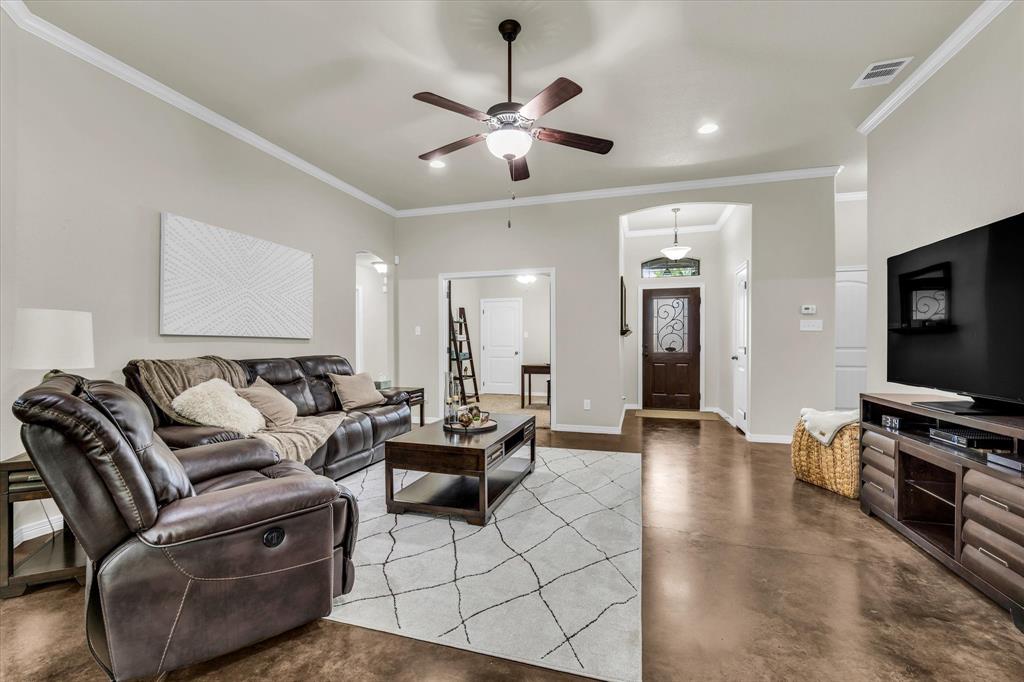 814 Springdale Circle Lorena, TX 76655 - Photo 15 of 37 Spacious living area featuring high ceilings, crown molding, a ceiling fan with light fixture, and rich wood-finish flooring