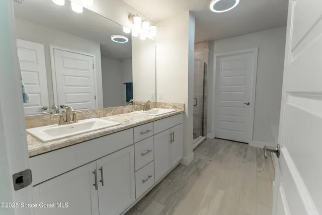 a bathroom with a double vanity sink and mirror with shower