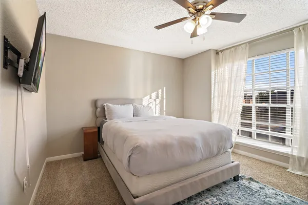 a bedroom with a bed a flat screen tv and a window