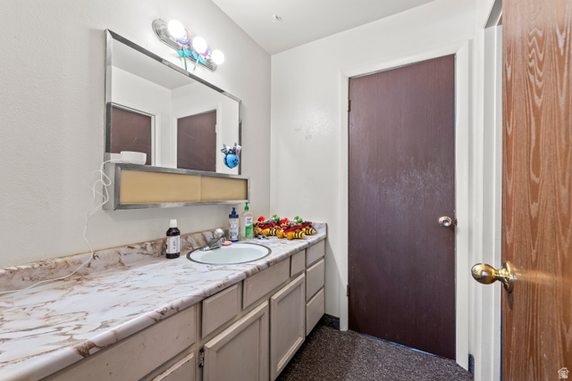 2475 West 200 North Provo, UT 84601 - Photo 9 of 16 Bathroom featuring a vanity with a white countertop and integrated sink, a large wall-mounted mirror, and a three-bulb light fixture