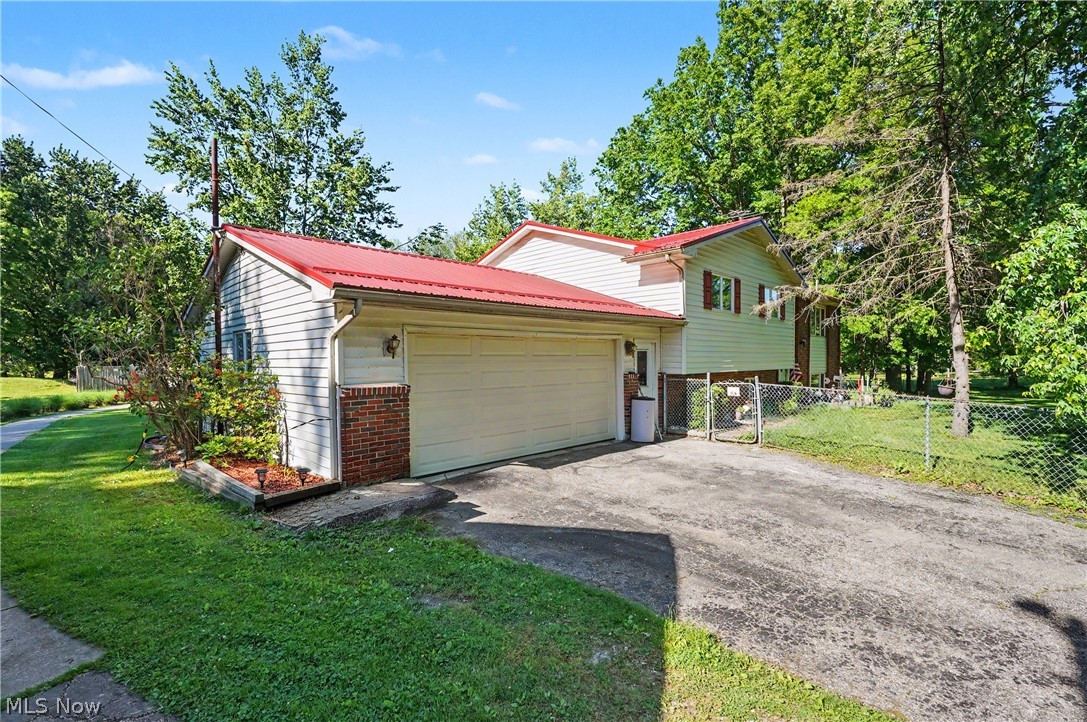 4250 Herr Fieldhouse Road Southington, OH 44470 - Photo 2 of 50 Exterior featuring a red metal roof, light-colored siding, and a brick accent foundation