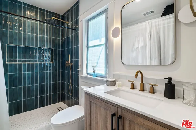 a bathroom with a sink a toilet a mirror and shower