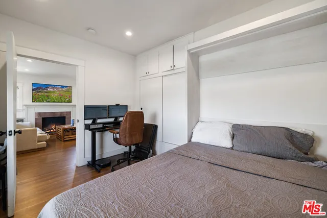 a bedroom with a bed computer on desk and a chair
