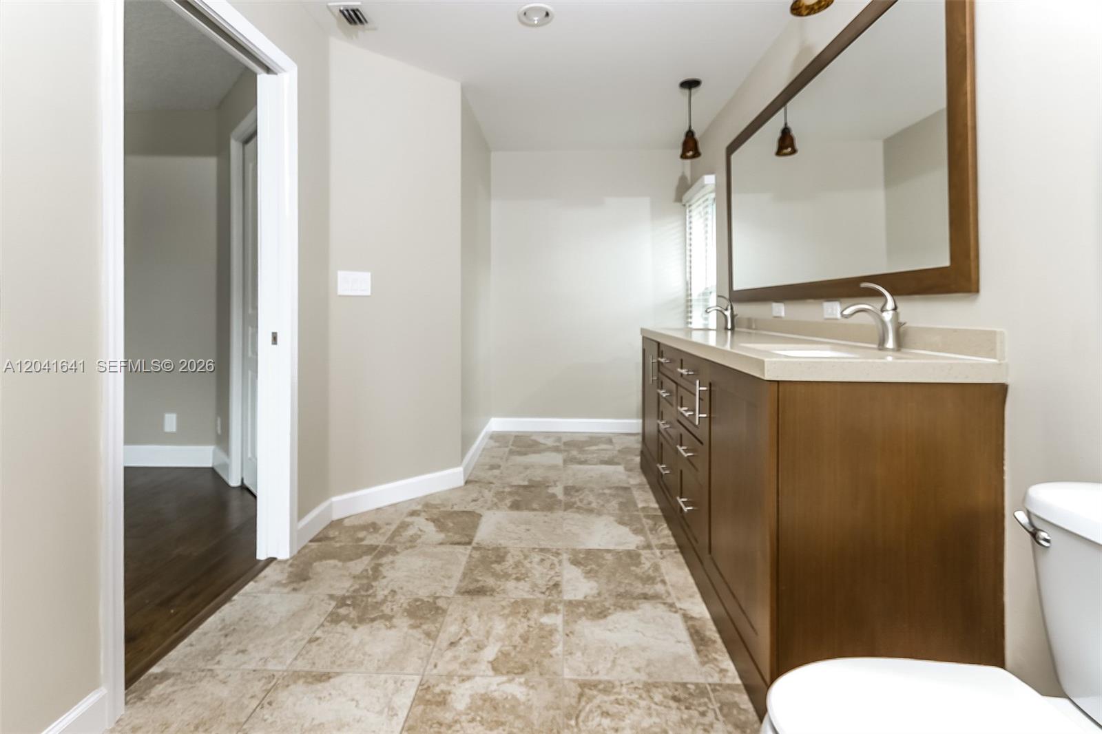 6484 Robinson Street Jupiter, FL 33458 - Photo 13 of 15 a bathroom with a sink a toilet a mirror and vanity