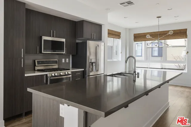 a view of a kitchen with kitchen island a counter top space a sink stainless steel appliances and cabinets