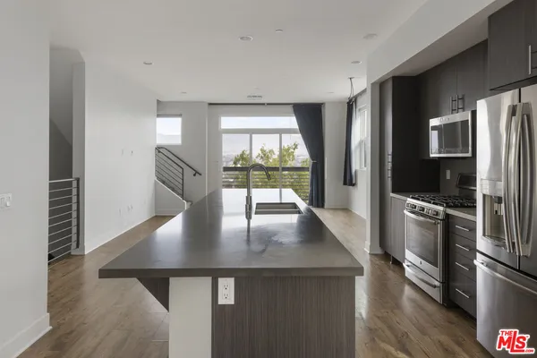 a kitchen with stainless steel appliances granite countertop a refrigerator a stove and a sink with wooden floor