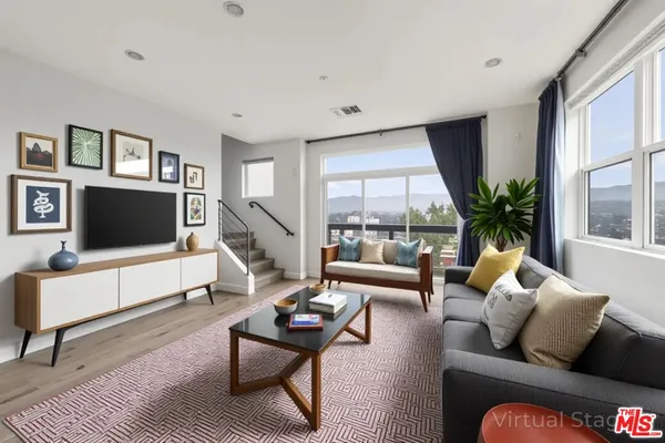 a living room with furniture flat screen tv and a large window