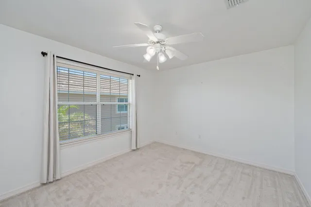 an empty room with a window and a fan