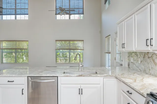 a kitchen with stainless steel appliances granite countertop white cabinets sink and window