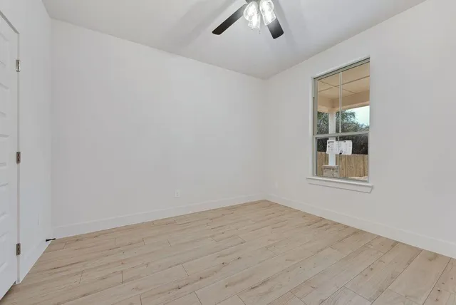 a view of an empty room with wooden floor and a window