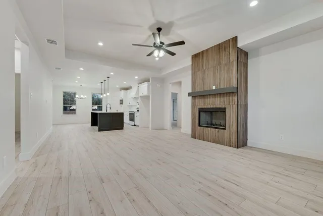 a view of kitchen and empty room with wooden floor