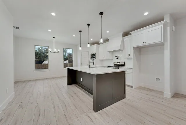 a kitchen with kitchen island a sink stainless steel appliances and cabinets