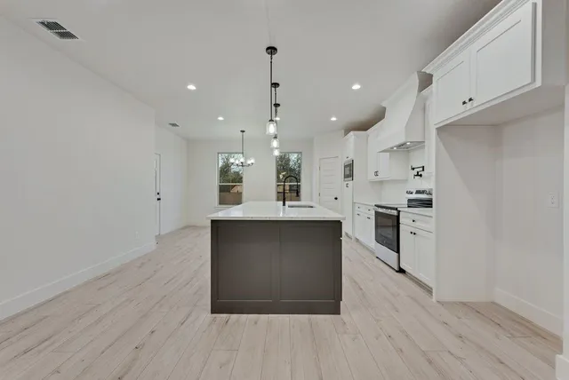 a kitchen with stainless steel appliances kitchen island wooden floors and white cabinets