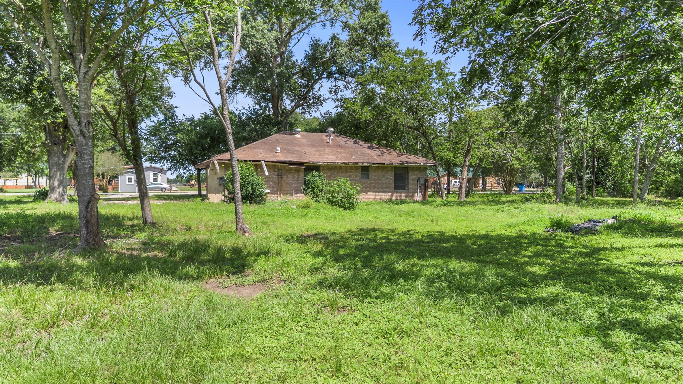 2701 Mazen Road Rosenberg, TX 77471 - Photo 8 of 10 A cozy brick house set amidst a spacious, lush green yard with mature trees, offering privacy and a serene outdoor environment.