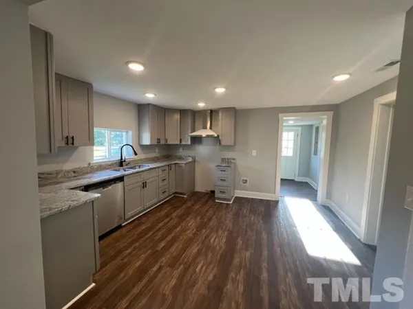 a kitchen with stainless steel appliances granite countertop a refrigerator a sink dishwasher a stove and white countertops with wooden floor