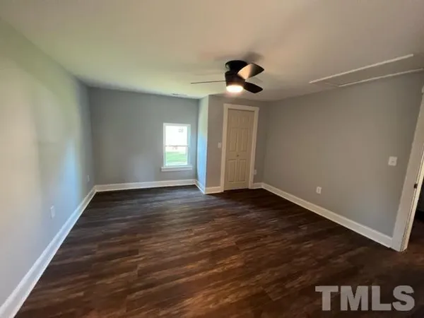 a view of an empty room with wooden floor and a window