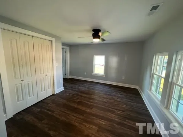 an empty room with wooden floor and windows