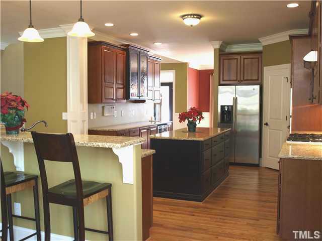 12316 Beestone Lane Raleigh, NC 27614 - Photo 6 of 20 a kitchen with granite countertop a refrigerator a sink dishwasher a dining table and chairs with wooden floor