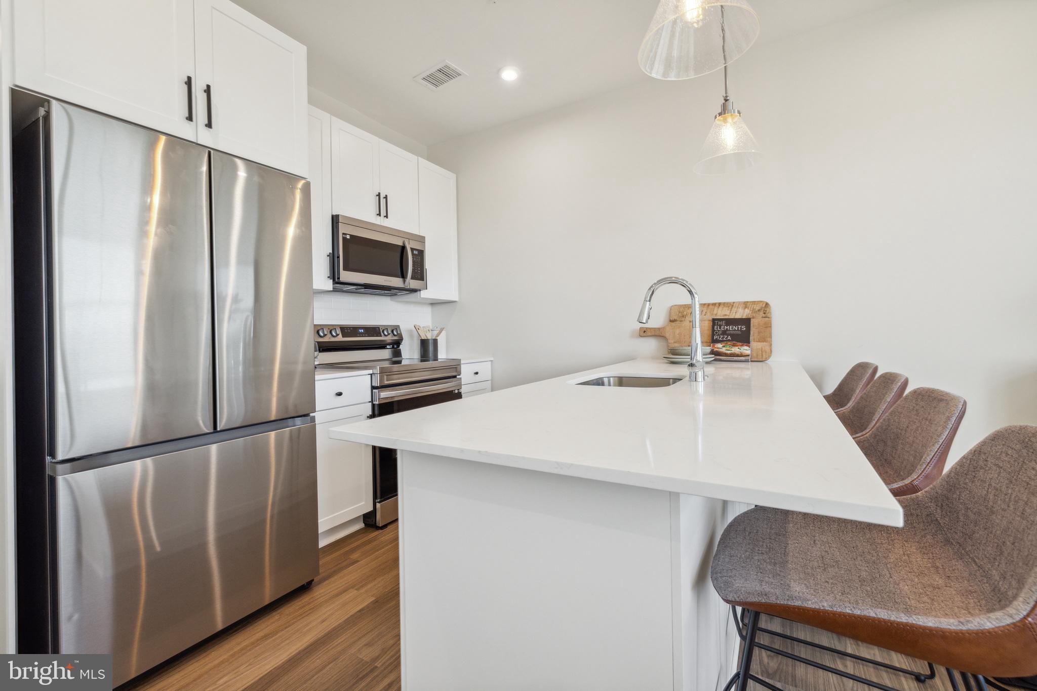 17 Mainland Road, Unit 217 Harleysville, PA 19438 - Photo 5 of 23 a kitchen with kitchen island a refrigerator stove and microwave