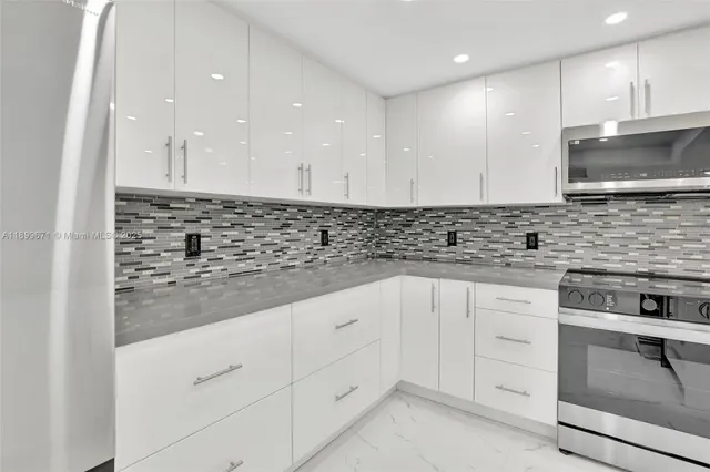 a kitchen with granite countertop white cabinets and stainless steel appliances