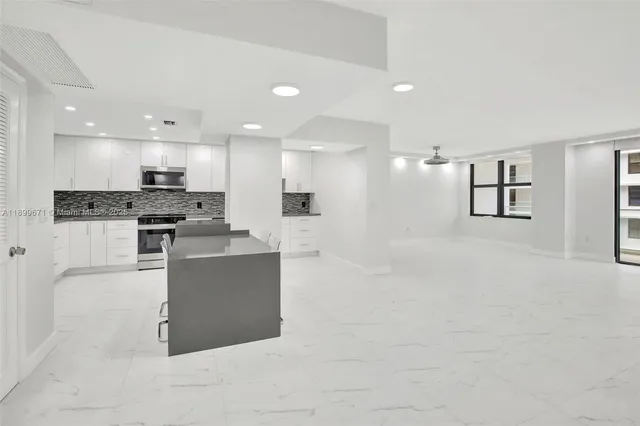 a large white kitchen with kitchen island a sink a stove and white cabinets