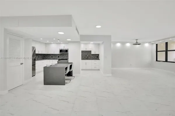 a view of kitchen with kitchen island stainless steel appliances refrigerator sink and microwave