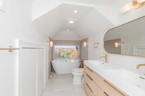 a spacious bathroom with a granite countertop sink a toilet a mirror and shower