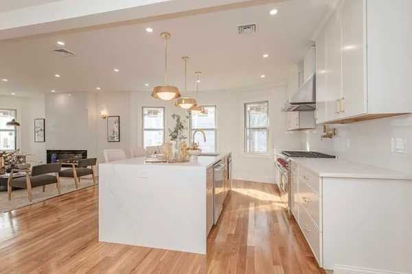 a large kitchen with kitchen island a stove a sink a refrigerator and a dining table with wooden floor