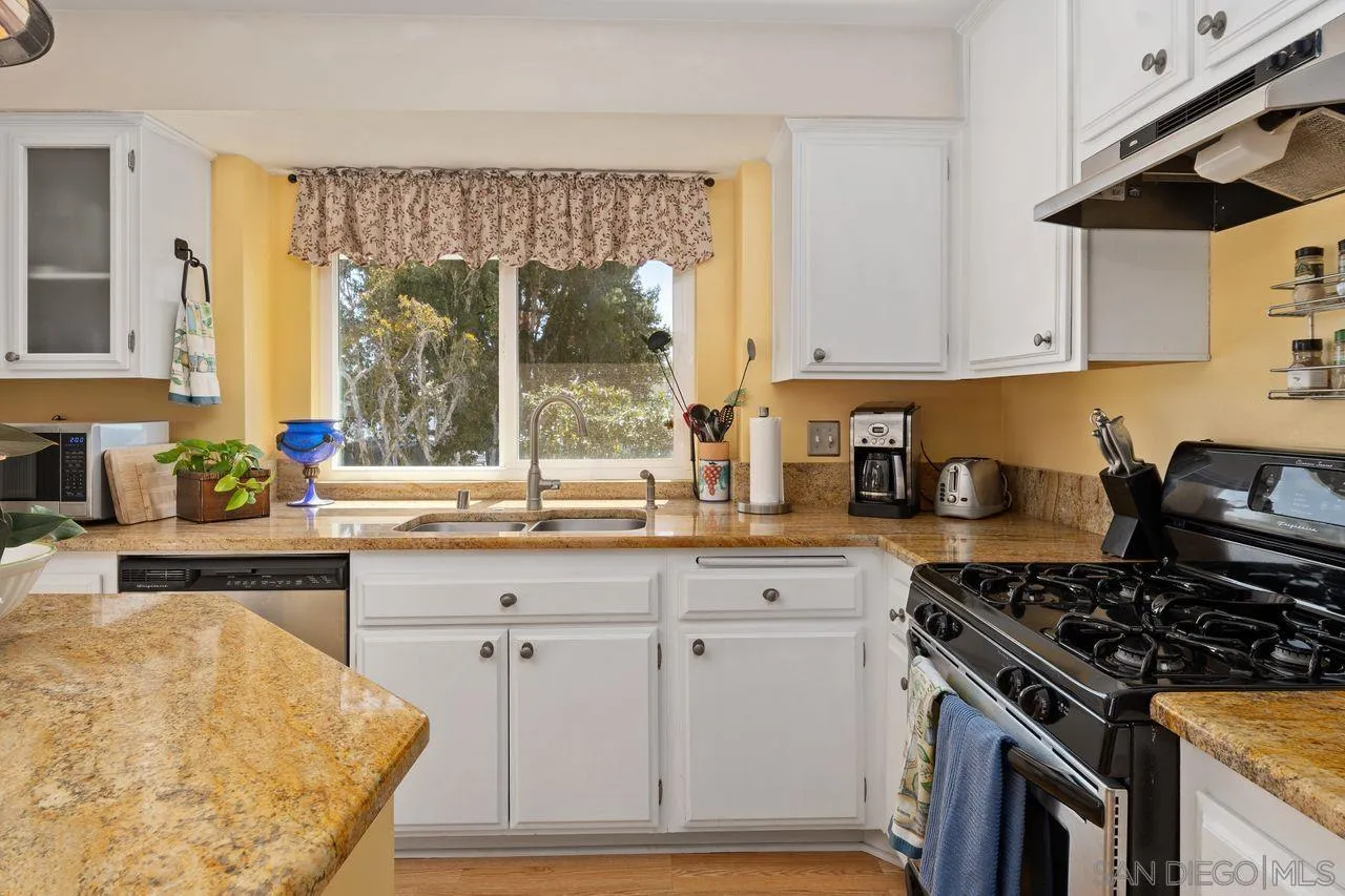 839 Mistletoe Lane Carlsbad, CA 92011 - Photo 14 of 50 a kitchen with granite countertop a stove a sink dishwasher and white cabinets with wooden floor
