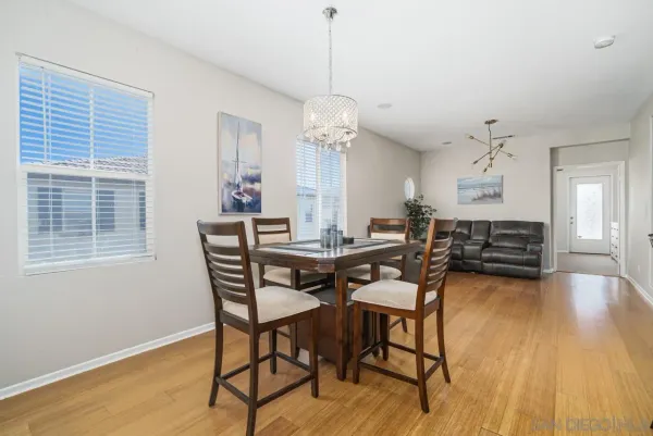 a dining room with wooden floor a chandelier a wooden table and chairs