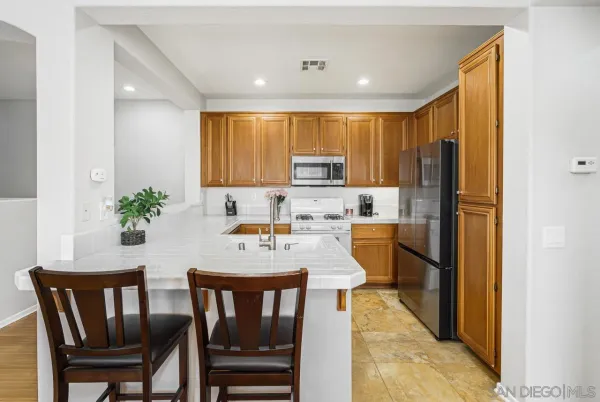 a kitchen with stainless steel appliances a dining table chairs and a refrigerator