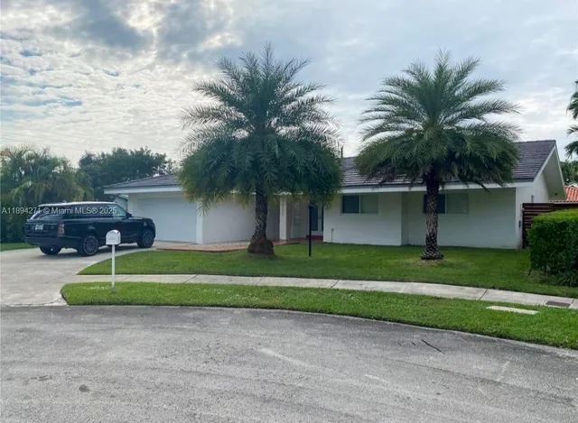 a palm tree sitting in front of a house with a large trees