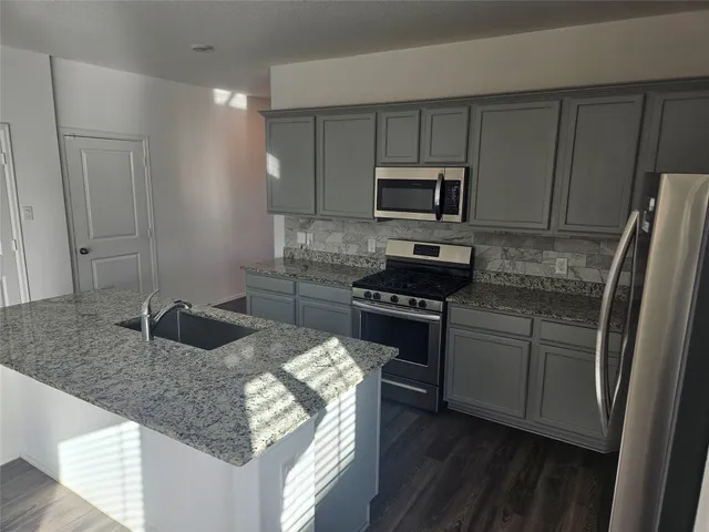 a kitchen with granite countertop a sink stove and refrigerator